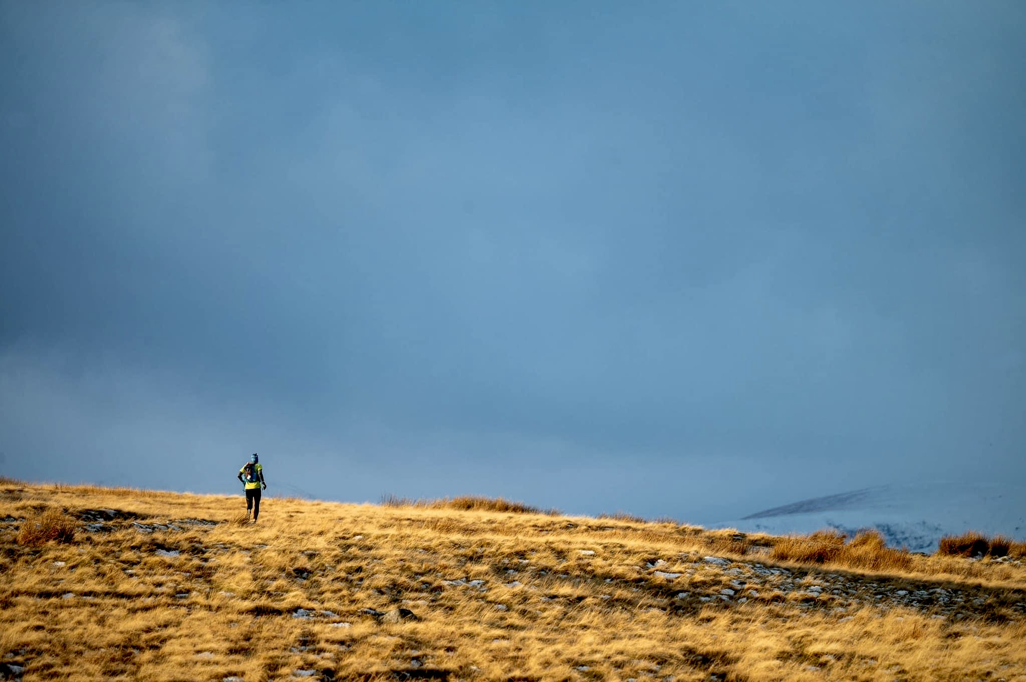 A beautiful bleak landscape with a lone runner on the horizon.