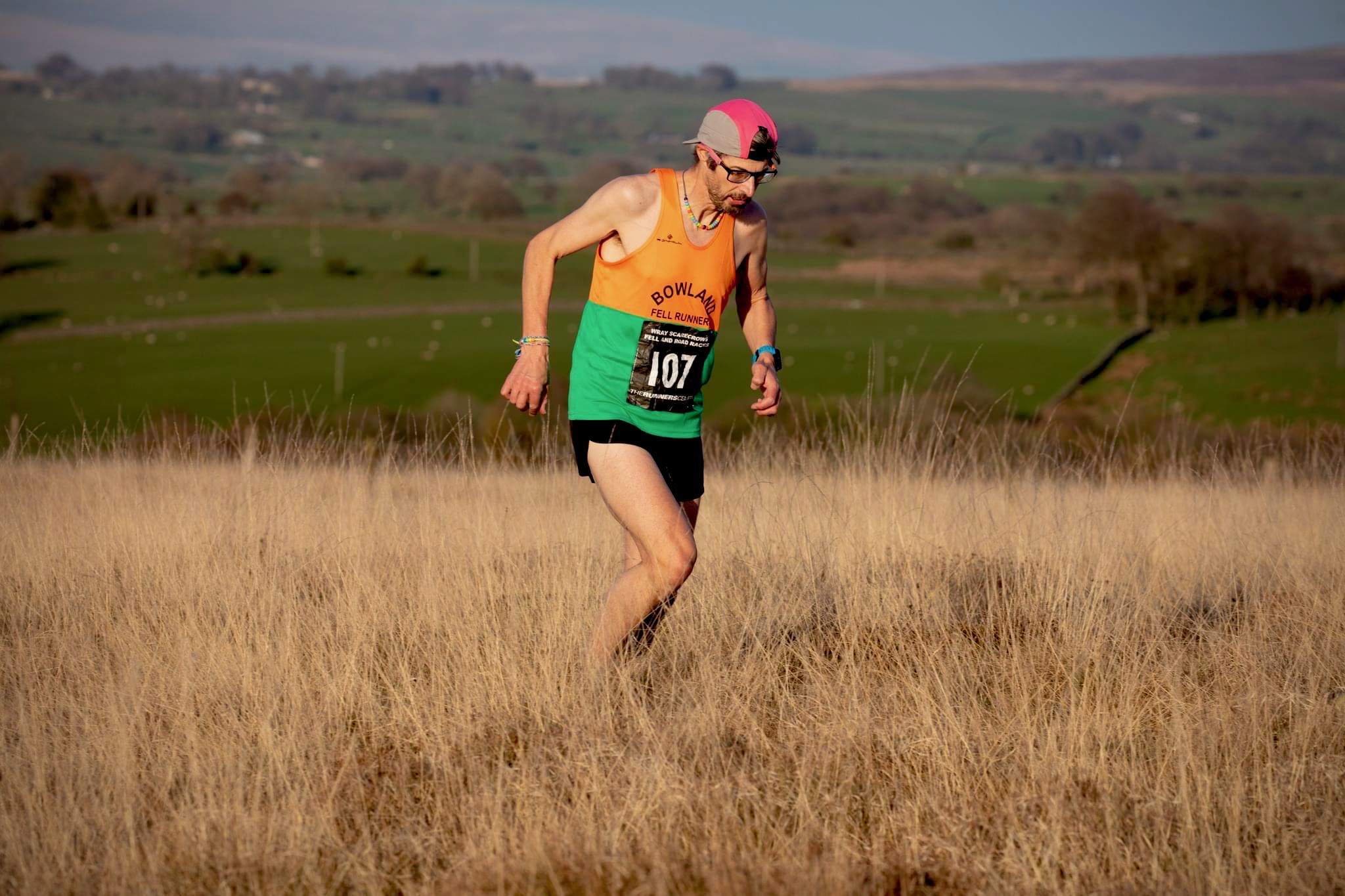 Man running on a fell with a strained expression on his face.