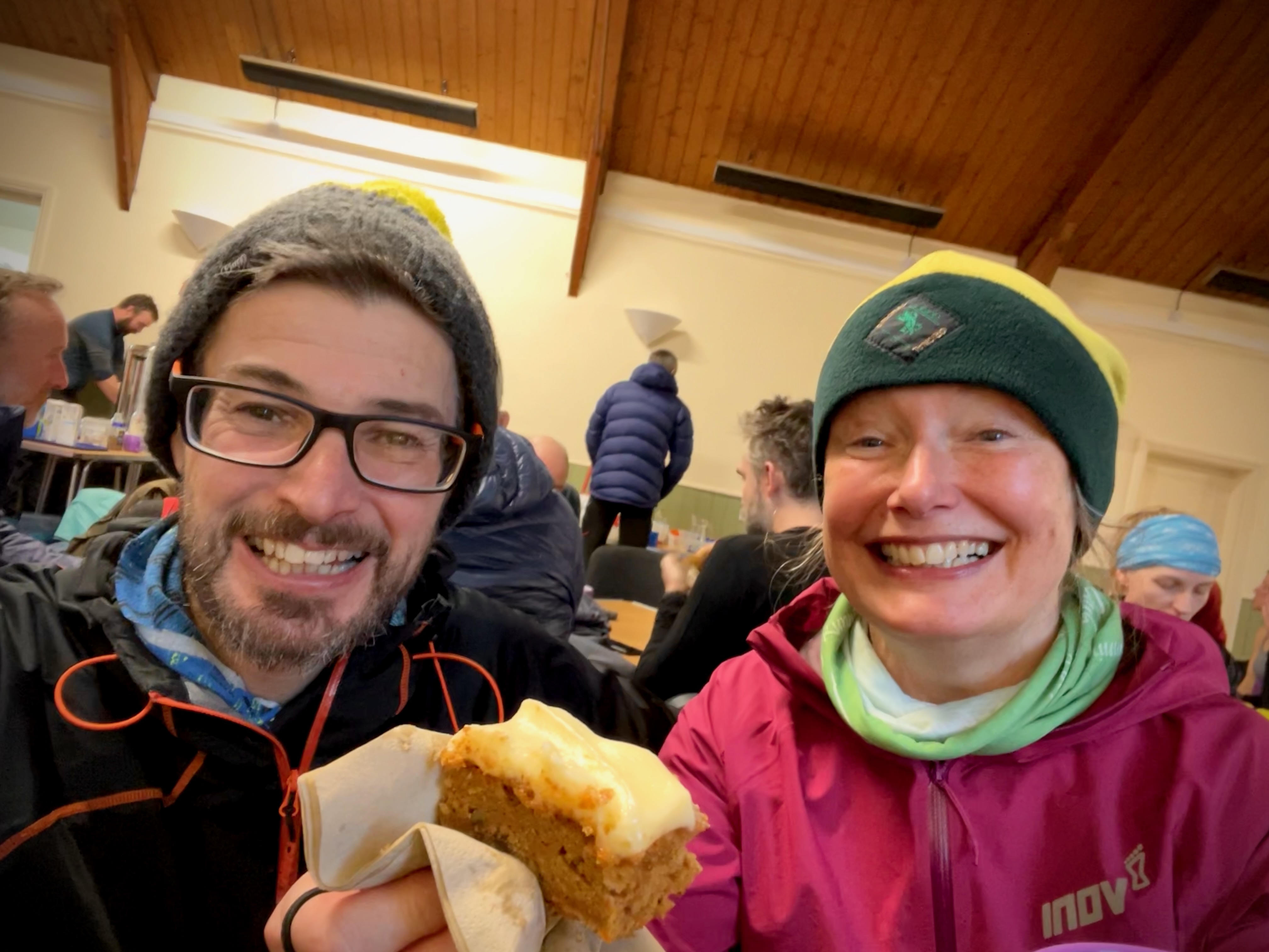 Two happy faces at Askham village hall, one is holding cake.