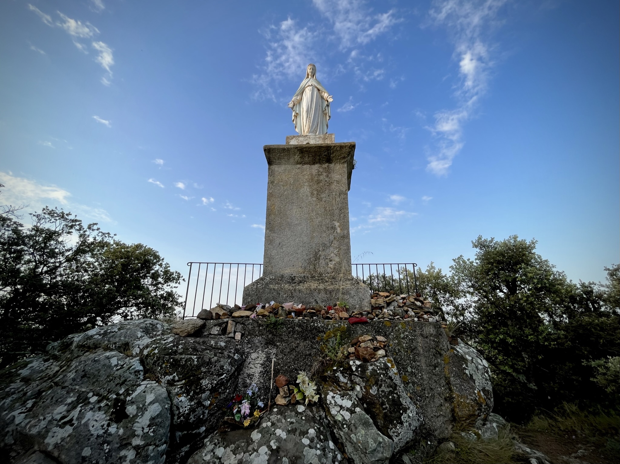 A religious statue in the foreground with beautiful blue sky beyond.