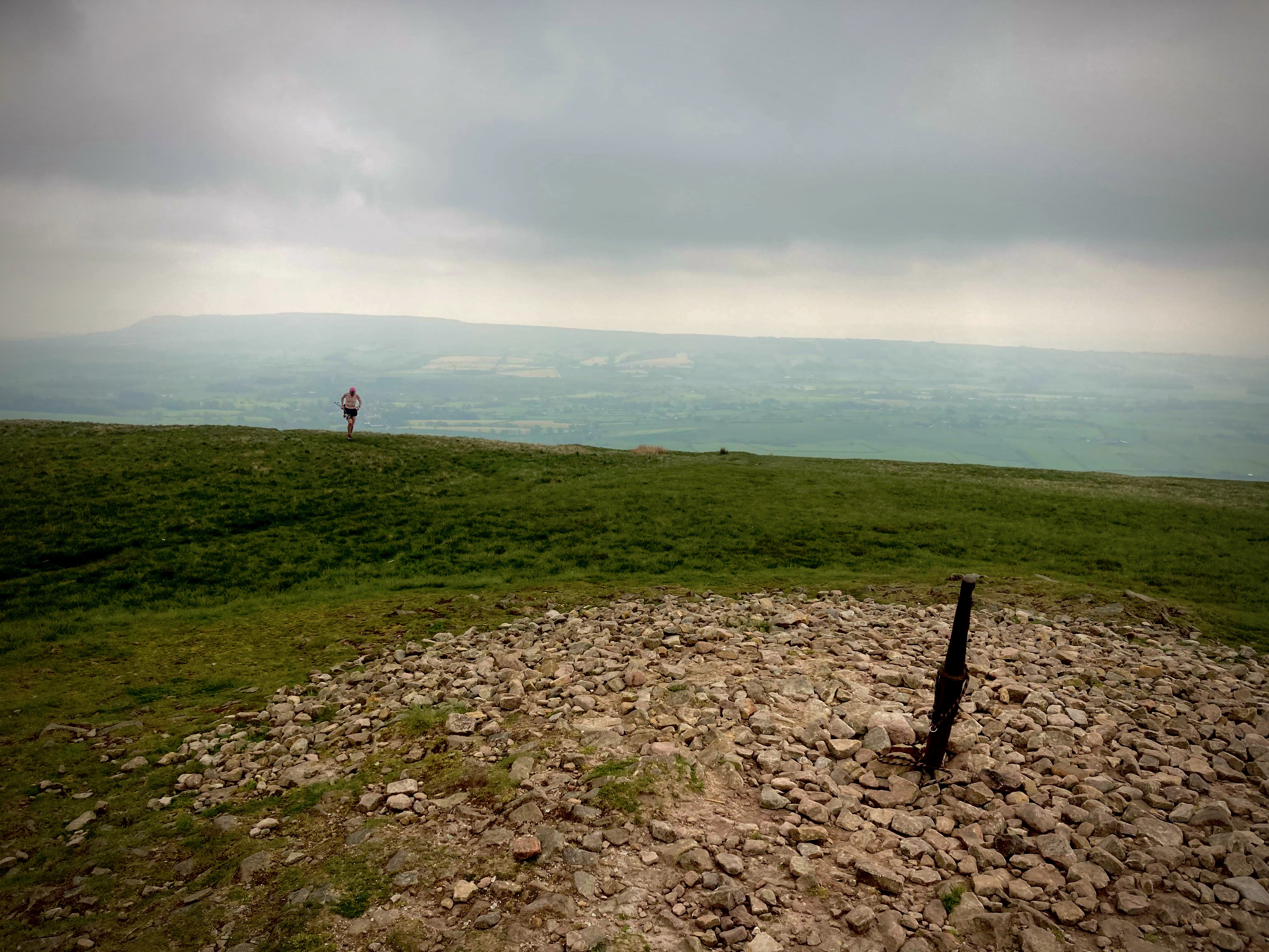 A runner approaching a trig point summit.